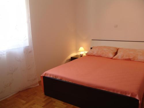 una camera da letto con un letto arancione e una finestra di Apartment Ines a Medulin