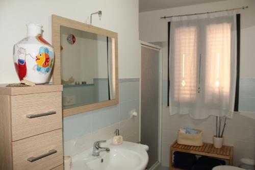 W łazience znajduje się umywalka, lustro i waza. w obiekcie Pretty Home w mieście Acireale