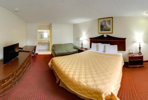 a hotel room with a bed and a flat screen tv at Key West Inn - Newport News in Newport News