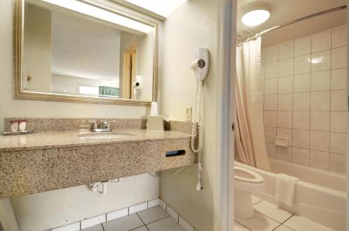 a bathroom with a sink and a toilet and a mirror at Key West Inn - Newport News in Newport News