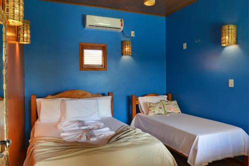 twee bedden in een kamer met blauwe muren bij Pousada vila de pescador in Atins