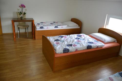 a bedroom with two beds and a table with a chair at Pansion Modana Medjugorje in Međugorje