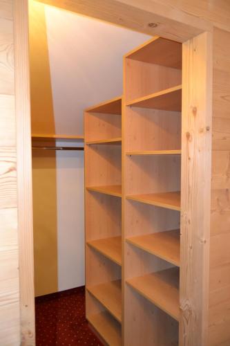 a closet with wooden shelves next to a refrigerator at Häuslerhof in Maranza