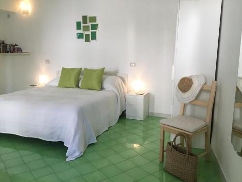 een slaapkamer met een wit bed en een stoel bij Casa Vuolo in Atrani