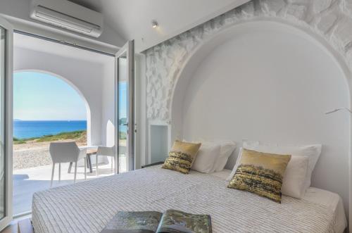 sypialnia z łóżkiem i widokiem na ocean w obiekcie Cyano Suites w mieście Naksos