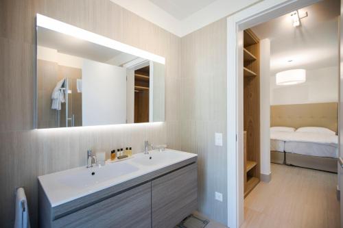 a bathroom with a sink and a mirror and a bed at Delta Resort Apartments in Ascona