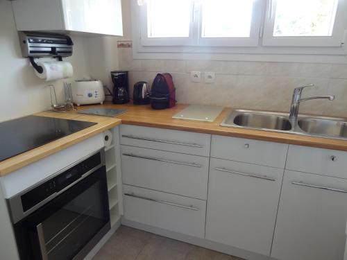 une cuisine avec des armoires blanches et un évier dans l'établissement VUE MER - Appartement T2, à Cannes