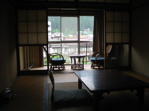 una stanza con sedie e tavolo e una grande finestra di Miharaya Ryokan a Gujo