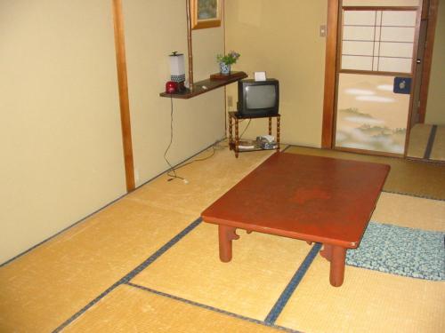 a living room with a coffee table and a tv at Miharaya Ryokan in Gujo