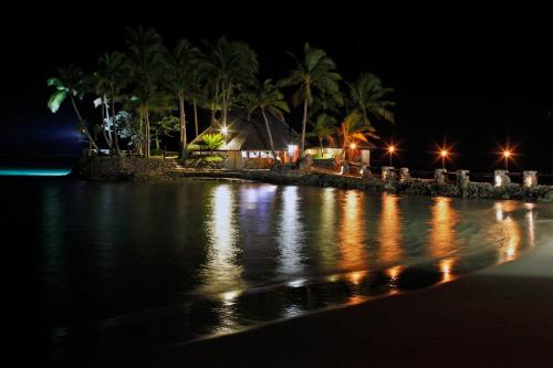 a beach at night with palm trees and lights at The Warwick Fiji in Korolevu