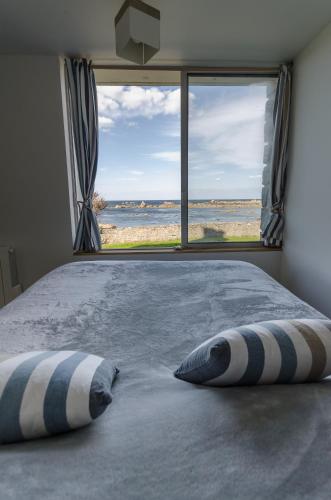 une chambre avec un lit avec vue sur l'océan dans l'établissement Maison de La pointe, à Brignogan-Plage