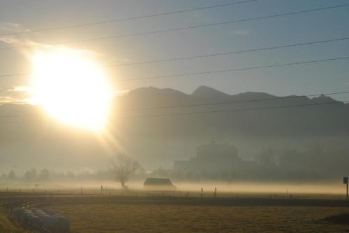 a foggy field with the sun in the background at Apartment Fewo Irdning Pichlarn in Aigen im Ennstal