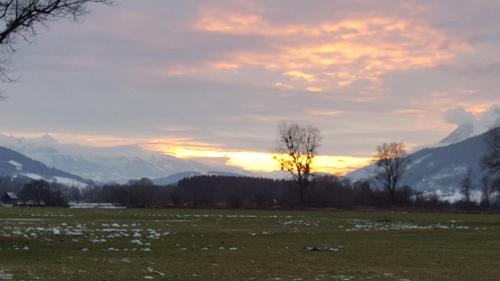 a field with mountains in the background with a sunset at Apartment Fewo Irdning Pichlarn in Aigen im Ennstal