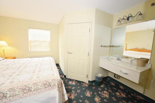 a hotel room with a bed and a dresser at OurGuest Inn & Suites Downtown Port Clinton in Port Clinton