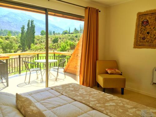 a bedroom with a balcony with a table and a chair at San Francisco Lodge in Los Andes