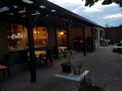 a patio with tables and chairs under a pergola at Landgasthof Schänzer in Voerde