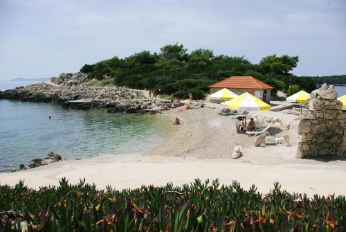 a beach with umbrellas and people sitting on the sand at Hotel Priscapac Resort & Apartments in Prizba