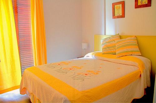 a bedroom with a bed with an orange blanket and a window at Dunas I, 3 in Pinamar
