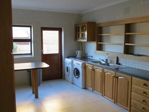 uma cozinha com um lavatório e uma máquina de lavar roupa em Cape Oasis Guesthouse em Bloubergstrand