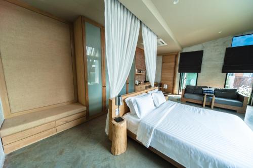 a bedroom with a bed and a couch in a room at Sea Two Pool Villa Resort Pattaya in Jomtien Beach