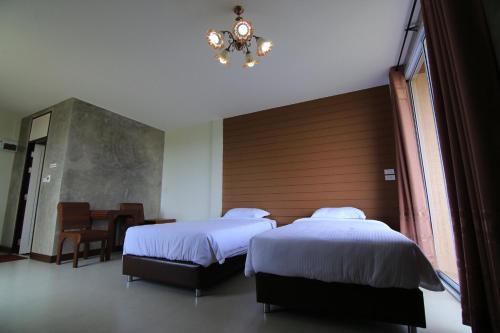 a bedroom with two beds and a chandelier at Nava Resort in Nakhon Nayok