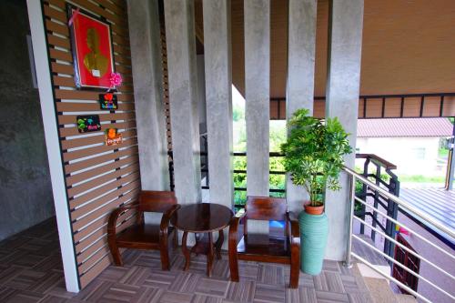 a porch with two chairs and a table and a plant at Nava Resort in Nakhon Nayok