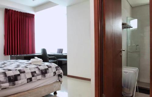 a bedroom with a bed and a chair in a room at Green Bay Condominium by Kevin in Jakarta