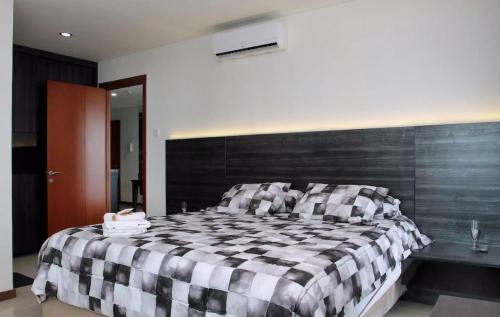 ein Schlafzimmer mit einem schwarz-weiß karierten Bett in der Unterkunft Green Bay Condominium by Kevin in Jakarta