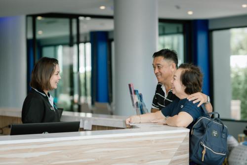 un grupo de tres personas sentadas en un escritorio en Krabi SeaBass Hotel en Krabi