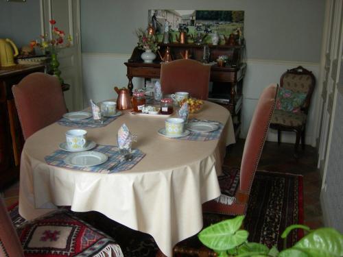 a dining room table with a white table cloth and chairs at La Ferme Rose in Cergy
