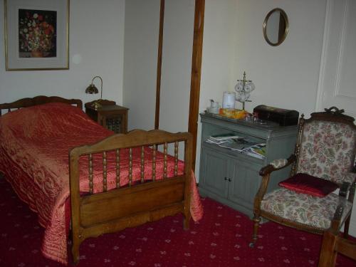 une chambre avec un lit, une commode et une chaise dans l'établissement La Ferme Rose, à Cergy