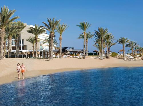 two women walking on the beach near the ocean at Constantinou Bros Pioneer Beach Hotel in Paphos