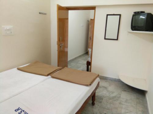 a room with a bed and a tv on a wall at MSR Lodge in Tirupati