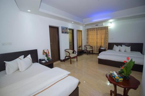 a hotel room with two beds and a table at Hotel Progati Inn Ltd. in Dhaka