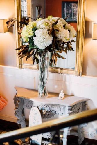 a vase of flowers on a table in front of a mirror at Castel Jolly in Rennes