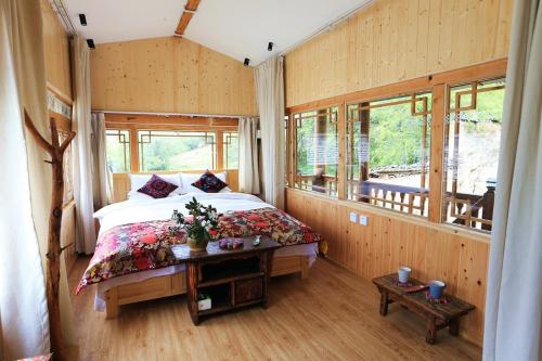 a bedroom with a bed in a room with windows at Shangri-La mid - mountain homestay in Shangri-La