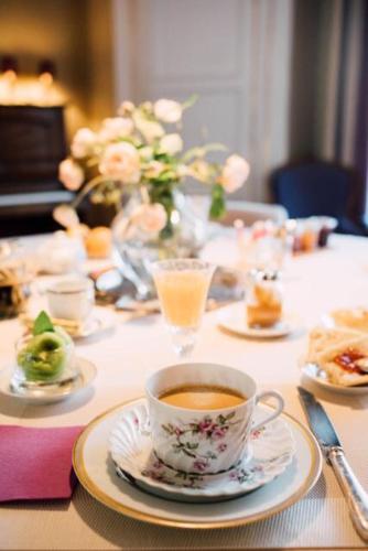 a table with a cup of coffee and plates of food at Castel Jolly in Rennes
