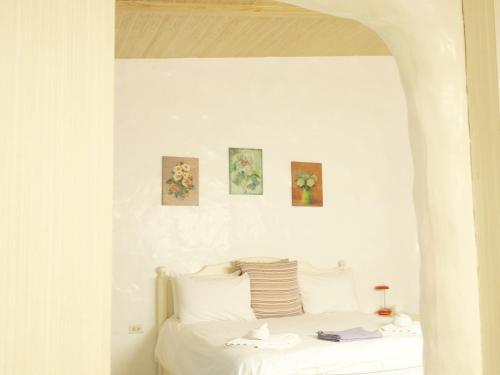 a white bed with four paintings on the wall at Costa Village Pool Villa in Jomtien Beach