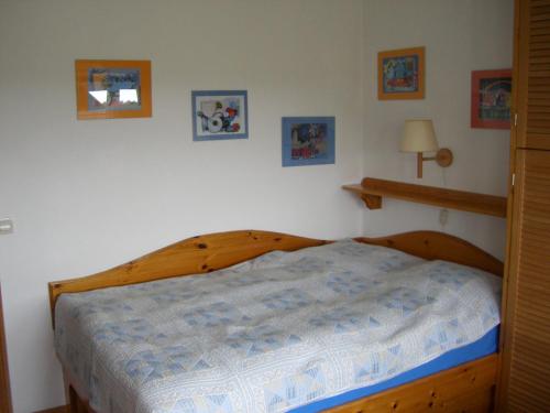 a bedroom with a wooden bed with a blue comforter at Gästehaus Kapitän Jan Ricklefs in Nebel