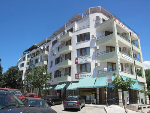 a tall white building with cars parked in front of it at Family Hotel Bistritsa in Sandanski