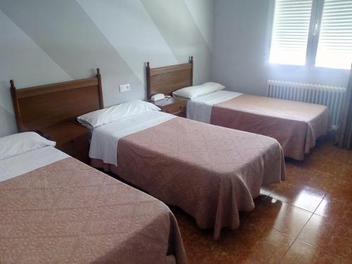 a hotel room with three beds and a window at Hotel Europa in Tomelloso