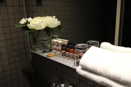 Kirketon Hotel Sydney في سيدني: منضدة حمام مع إناء من الزهور البيضاء والجرارات