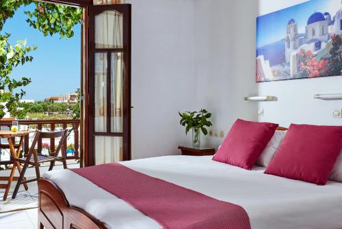 sypialnia z łóżkiem z czerwonymi poduszkami i balkonem w obiekcie Paul Marie w mieście Hersonissos