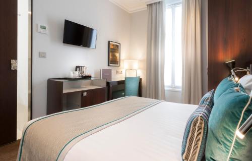 a hotel room with a bed and a desk and a television at Montfleuri in Paris