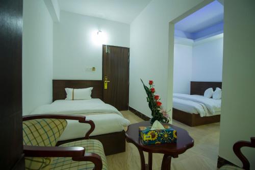 a hotel room with two beds and a chair and a table at Hotel Progati Inn Ltd. in Dhaka