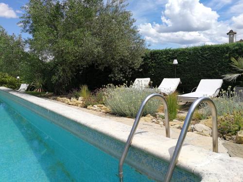 Deaux桑树庄园度假屋的游泳池旁设有两把白色椅子