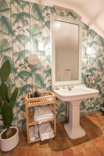 La salle de bains est pourvue d'un lavabo, d'un miroir et d'une plante. dans l'établissement Hostellerie La Montagne, à Colombey-les-Deux-Églises