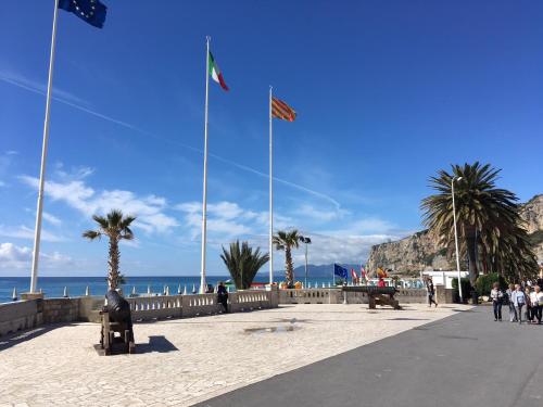 people walking on a sidewalk near the beach with flags at Hotel Europa in Finale Ligure