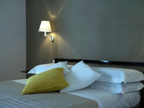 a bedroom with two beds with white pillows and a lamp at Talè Restaurant & Suite in Piedimonte Etneo