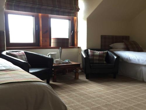 a hotel room with two chairs and a bed at Garfield Guesthouse in Dingwall